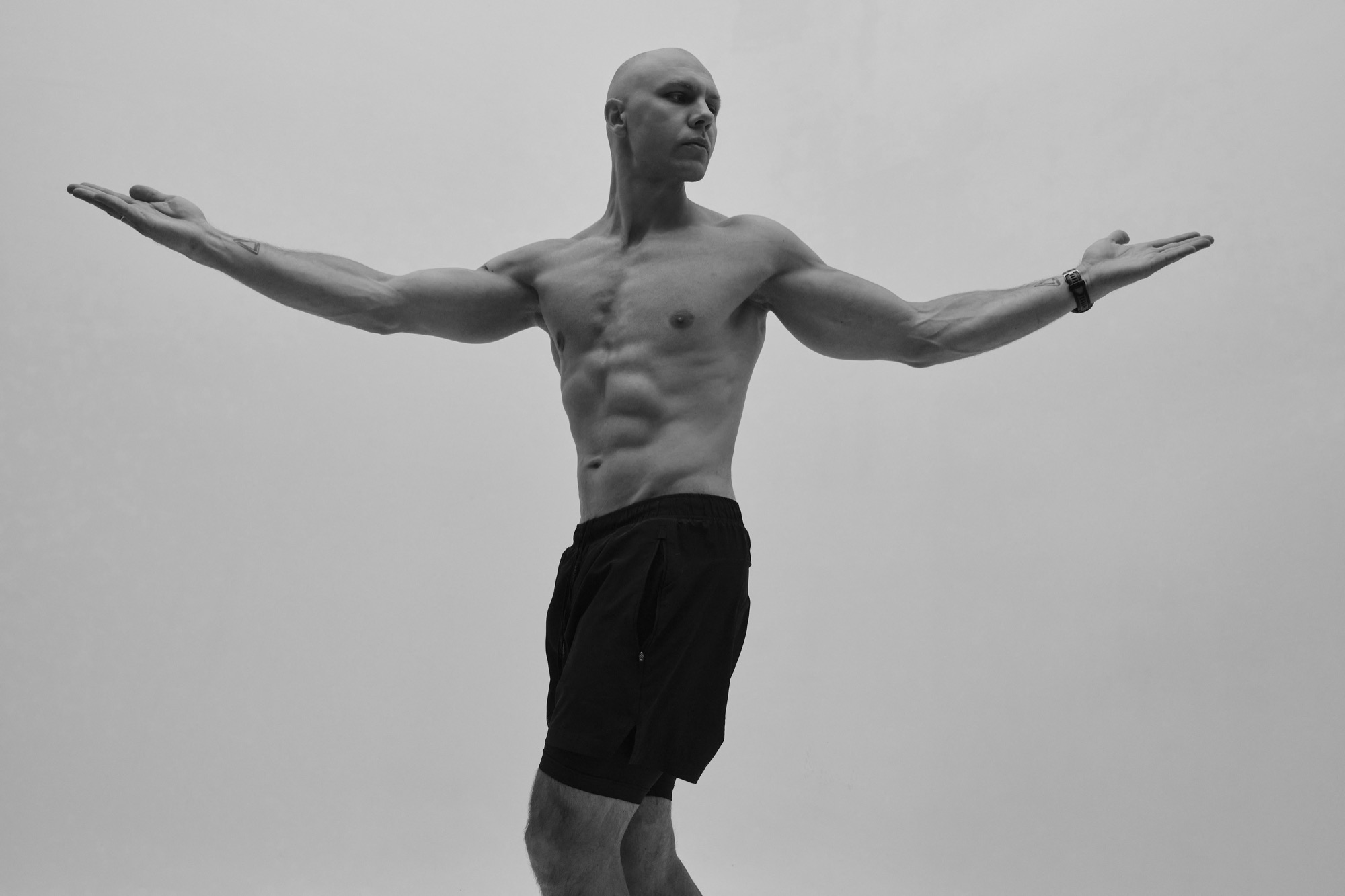 A man standing with his arms spread wide against a pale background